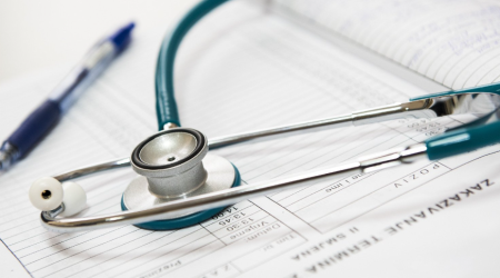 A stethoscope and a pen placed on paperwork.